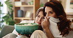 Friends, scared and popcorn in house for movie, television and streaming online video with subscription. Women, horror and eating snack in living room for watching tv, bonding and relax with blanket