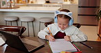 Child, girl and writing homework with headphones at dining table for education, elearning or listening to music. Student, laptop or happy with study podcast in home with notebook, learning or project