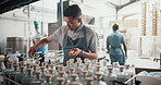 Employee, man and packaging alcohol at distillery with gin bottles for manufacturing and production at warehouse. Male person, business and serious with stocktaking at factory for delivery and supply