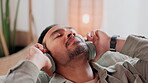 Home, relax and man with headphones on sofa for entertainment, streaming and listening to music. Sound, technology and person with eyes closed in living room for audio, peace and song on playlist