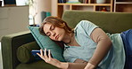 Online, relax and bored woman on sofa with phone for website, internet or social media at home. Scroll, communication and student laying on couch with smartphone, app and entertainment in living room