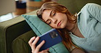 Online, video and bored woman on sofa with phone for website, internet or social media at home. Watch, communication and student laying on couch with smartphone, app and entertainment in living room