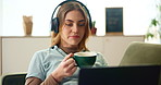 Girl, relax and headphones with laptop on sofa for listening music, education podcast and coffee break. Woman, laugh and digital with headset for streaming, herbal tea and audio sound on web at house