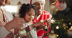 People, child and decorate on Christmas tree for festive, holiday and celebration as happy family in home. Parents, bonding and daughter with ornaments, lights and living room on vacation in December