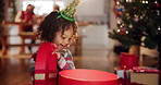 Happy child, girl and gift on Christmas for celebration or festive holiday in home on winter vacation. Female person, toddler and playful with present or surprise in living room for event in December