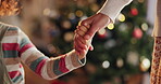 Christmas, family and parent holding hands with child closeup in living room of home for celebration. December, festive and holidays with people together in apartment for love, support or tradition