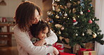 Christmas, hug and mother with girl, home and celebration with festive holiday, care and bonding together. Apartment, family and Xmas tree with presents, smile and embrace with joy, love or happiness