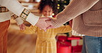 Christmas, family and holding hands in home for prayer, worship and spirituality or love. Child, parents and gesture in living room for Christian faith, praise and religious celebration in December