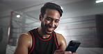 Boxing, happy and man in gym with phone checking meme, online chat or funny social media video. Laughing, smile and boxer in ring with smartphone reading fitness app, text or post at sports club