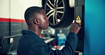 Mechanic, engineer and car lift with black man in garage, service center and transport industry. Workshop, auto repair and African repairman working on vehicle for maintenance, safety and motor care