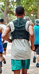 Running, nature and back of black man in marathon with group for outdoor exercise, competition or fitness. Sports, energy and male athlete with cardio workout in race with crowd for contest in park.