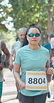 Running, nature and woman in marathon with group for outdoor exercise, competition or fitness. Sports, energy and mature female athlete with cardio workout in race with crowd for contest in park.