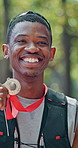 Medal, happy and face of black man at race in nature with pride for fitness goal or achievement. Winner, excited and portrait of African male athlete with gold award for marathon with cardio exercise