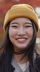 Face, smile and Japanese woman outdoor with wind in hair on holiday, vacation or travel to relax. Portrait, happiness and Asian girl in nature with beanie for tourism, adventure and beauty in Japan