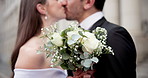 Kiss, love and couple with flowers for wedding, commitment ceremony or bonding together outdoor. Marriage event, people and groom with bride for roses bouquet, celebration or partnership with romance