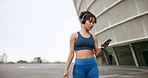 Woman, walking and exercise with smartphone, headphones and wellness with social media. New York, person and athlete with headset, training and cellphone with communication, listening to music or app