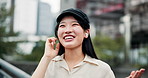 Japanese woman, earphones and wireless for communication, talking and entertainment in city. Female person, technology and happy for conversation, chat and social network on mobile app for connection