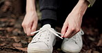 Hands, person and shoes tie for running, fitness and training outdoor with workout. Feet, runner and marathon exercise for race with health of athlete in Japanese park with sneakers on ground 