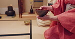Hands, person and Japanese herbal tea in cup at traditional ceremony or event for spirituality in Japan. Closeup, cultural clothes and heritage attire with teapot for matcha beverage and flavor