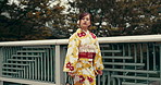 Travel, woman and walking in kimono on bridge for city adventure, exploring and journey in Japan park. Person, traditional yukata and commute outdoor in nature for weekend trip, holiday and vacation