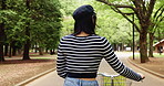 Relax, bike and back of Japanese woman in park for travel, carbon footprint and walking. Eco friendly, transportation and summer with asian person and bicycle in nature for cycling and wellness