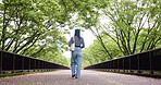 Japanese woman, back and travel at park outdoor for holiday, vacation or sightseeing trip with handbag. View, walking and female person at garden for journey, commute or tourist on road or bridge