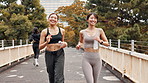 Happy, women and running in city for fitness, exercise and cardio training in Tokyo. Japanese people, friends and wellness on urban bridge with smile, routine and marathon preparation with greeting