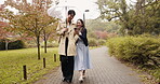 Umbrella, phone and Japanese couple in park for love, social media post and bonding together. Commitment, support and date with asian man and woman in nature for streaming, honeymoon and network