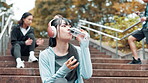 Woman, outdoor stairs and drinking water for exercise, running break and headphones for music. Female person, athlete relax and mineral liquid for thirst in Japan, sports and cardio rest in park