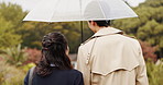 Park, umbrella and back of Asian couple walking for commute, journey and travel outdoors. Dating, autumn and man and woman in conversation, bonding and talking with protection for rainfall in Japan