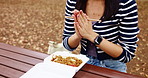 Woman, praying and hands in park with food, noodles and picnic bench in Japanese chopsticks with travel and break. Outdoor, takeaway and religion in autumn and Japan on weekend with meal and prayer