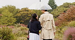 Park, umbrella and back of Asian couple in rain walking for commute, journey or travel outdoors. Dating, autumn and man and woman for bonding, talking or love with protection for water drops in Japan