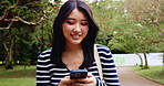 Japanese woman, walking and phone outdoor for communication, reading notification and social media. Girl, smile and journey with mobile for contact, texting and networking of nature travel in Japan