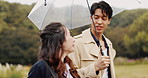 Walking, umbrella and Asian couple in park with rain for bonding, journey and travel outdoors. Nature, winter and Japanese man and woman in conversation with protection for drops, splash and water