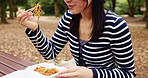 Woman, eating and park with Japanese food, chopsticks and picnic bench in forest with travel and college student break. Outdoor, takeaway and noodles in autumn and Japan on weekend with meal to relax