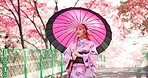 Woman, kimono and walk with umbrella in park, outdoor bridge and travel to park for thinking. Female person, traditional clothes and relax in nature for culture, local fashion and explore garden