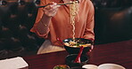 Eating, hands and ramen bowl in restaurant for nutrition, lunch and dinner meal with vegetables or noodles. Customer, person and food with chopsticks for healthy dish and traditional Japanese cuisine
