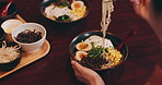 Japan, person and eating ramen in restaurant for nutrition, lunch and dinner meal with vegetables and egg. Customer, woman and noodles food with chopsticks for healthy dish and traditional cuisine