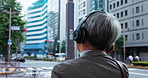 Mature man, headphones and street for business, thinking and listen to music with subscription on trip. Professional person, back and commute to workplace with streaming, walking and road in Japan