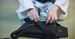 Aikido, black belt and hands of person in Japan dojo for combat skills, training and self defense. Martial arts, fight and discipline with closeup of uniform of student in class for club and safety