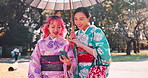 Friends, kimono and Asian women in city with phone for social media, connection and online chat. Travel, traditional fashion and Japanese people talking, in conversation and walking with smartphone