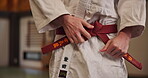 Martial arts, hands and man tying belt for sports, fitness and student ready for fight training in Japan. Aikido, knot and person with obi in dojo for exercise, preparation and uniform for workout
