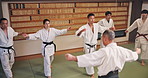 Training, coaching and people in aikido class together for group challenge, fitness and muscle warm up in club. Culture, mentor and students in dojo for traditional Japanese martial arts exercise.