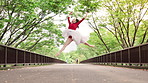 Woman, ballet and dancer with jump on bridge, moving and low angle in urban park for performance in spring. Person, dancing and outdoor with steps, creativity and talent for street art in Japan