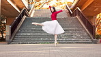 Woman, ballet and dancing in city with stretching, kick or outdoor by stairs with rhythm in street. Person, dancer and tutu for arabesque with steps, concert or performance on urban sidewalk in Japan