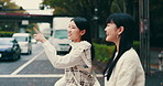 Women, walking and cross road in town of Japan, talking and friends travel together in city. People, sightseeing and adventure or urban journey on street, pointing and outdoor hangout for bonding