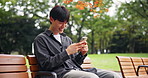 Japan, funny and man on bench, smartphone and humor with meme, laughing and network. Asian person, outdoor and guy in park, cellphone and joke with joy, social media and break with digital app
