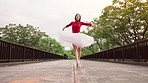 Woman, ballet and dancing with spin on bridge, moving and low angle in urban park for performance in spring. Person, dancer and balance for steps, creativity and tutu with talent with art in Japan