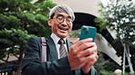 Mature business man, phone and city with texting, reading and excited for notification on commute to work. Person, smartphone and happy with mobile app, email or good news on urban sidewalk in Japan