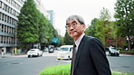 Mature business man, travel and street with traffic, thinking and waiting to cross road for commute to workplace. Person, check and outdoor in city on urban sidewalk, suit and journey in Japan